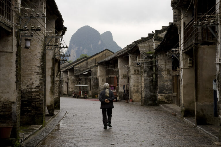 Old village street in Guangxi, China, showcasing traditional architecture and mountain backdrop.