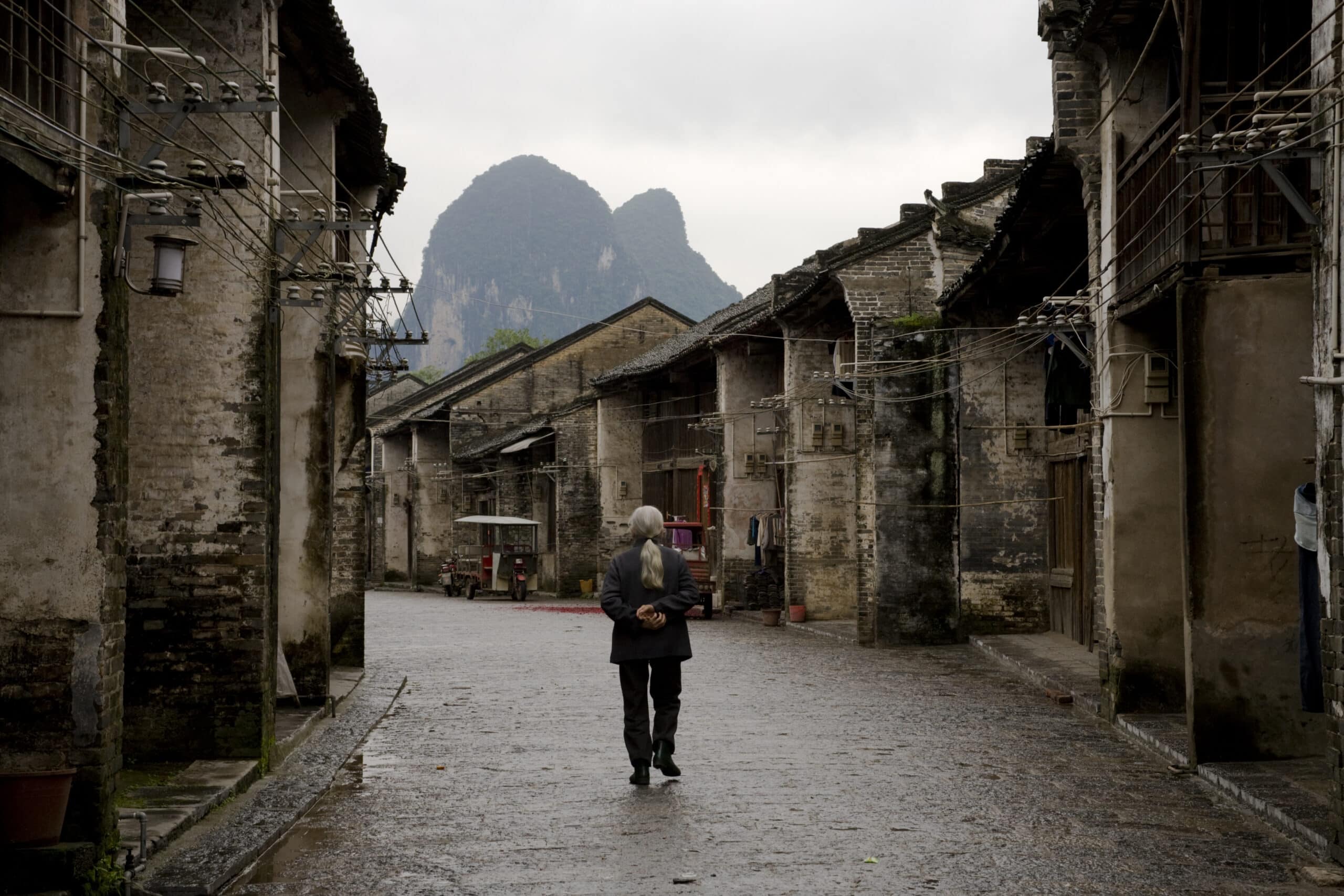 Old village street in Guangxi, China, showcasing traditional architecture and mountain backdrop.