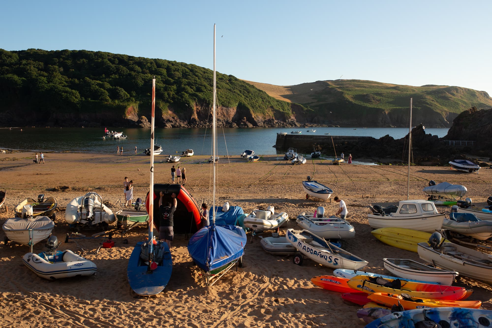 Boats and moorings at a scenic harbour in Cornwall, England, during sunset.