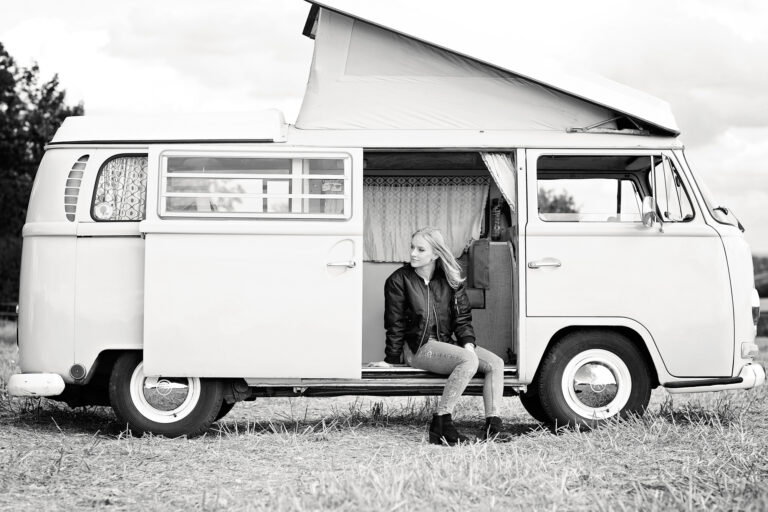 Vintage campervan with young woman sitting outside, outdoor photography, lifestyle, travel, black and white image.